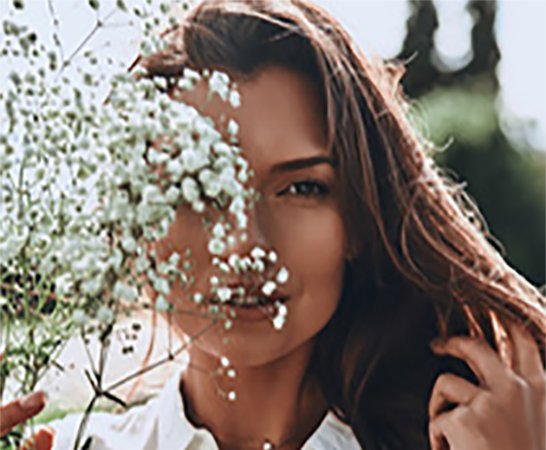 |Natural beauty. Attractive young smiling woman covering face with flowers|