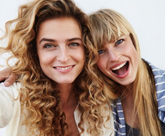Two young beautiful friends posing for camera