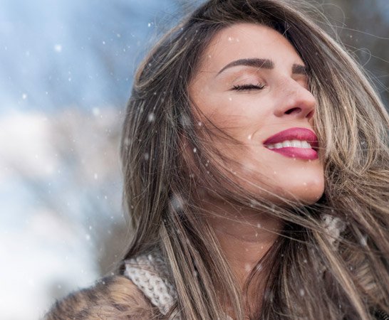 Woman in cold relieved from dry skin with body lotion