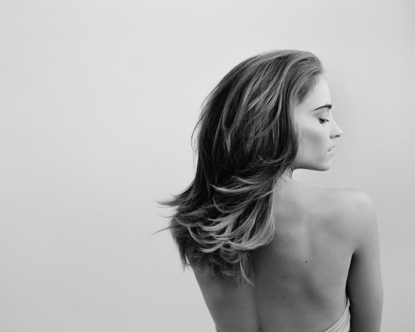 Black and white photo of a woman with shoulder-length hair facing away from the camera.